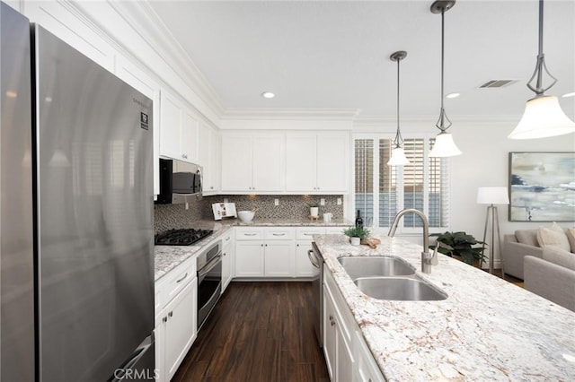 kitchen featuring a sink, dark wood finished floors, stainless steel appliances, crown molding, and decorative backsplash