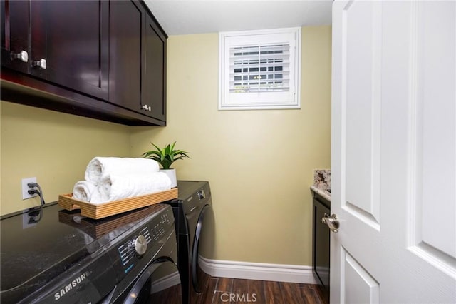 laundry room featuring cabinet space, dark wood-style floors, washer and dryer, and baseboards