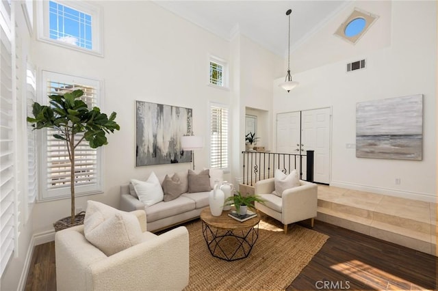 living room with dark wood finished floors, baseboards, visible vents, and high vaulted ceiling