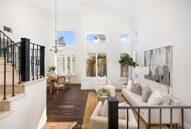 living room with stairway, wood finished floors, baseboards, visible vents, and a chandelier