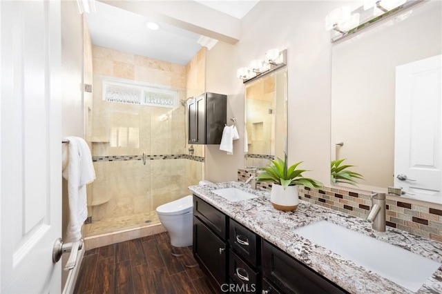 bathroom with decorative backsplash, wood finished floors, a stall shower, and a sink