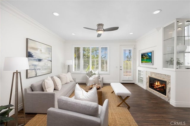 living room featuring crown molding, baseboards, a premium fireplace, recessed lighting, and dark wood-style floors