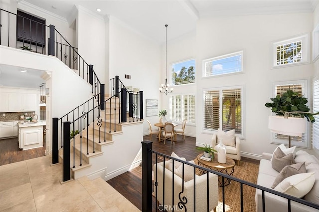 staircase with visible vents, baseboards, a chandelier, ornamental molding, and a towering ceiling