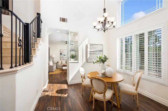 dining room with visible vents, baseboards, stairway, a towering ceiling, and wood finished floors