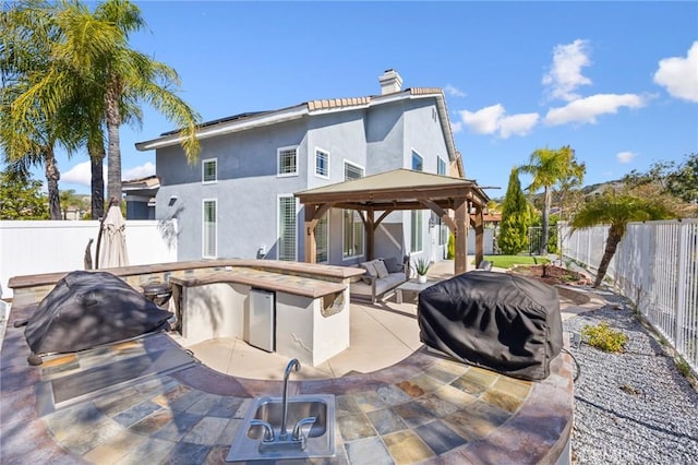 rear view of house with a patio, a fenced backyard, a chimney, stucco siding, and a gazebo