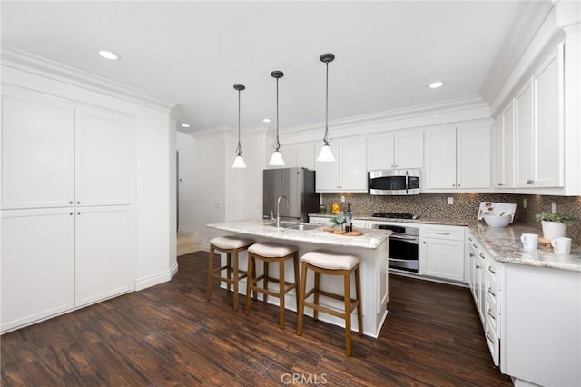 kitchen with a breakfast bar area, dark wood-style floors, a sink, stainless steel appliances, and backsplash