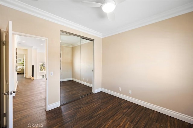 unfurnished bedroom with a closet, baseboards, dark wood-type flooring, and ornamental molding