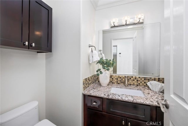 bathroom with decorative backsplash, toilet, ornamental molding, and vanity