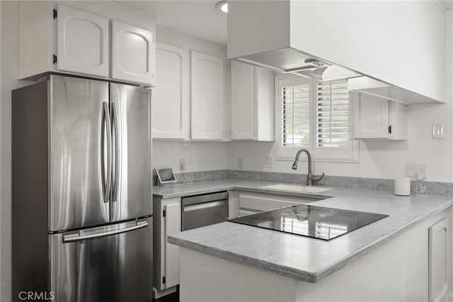 kitchen featuring a peninsula, a sink, white cabinets, light countertops, and appliances with stainless steel finishes