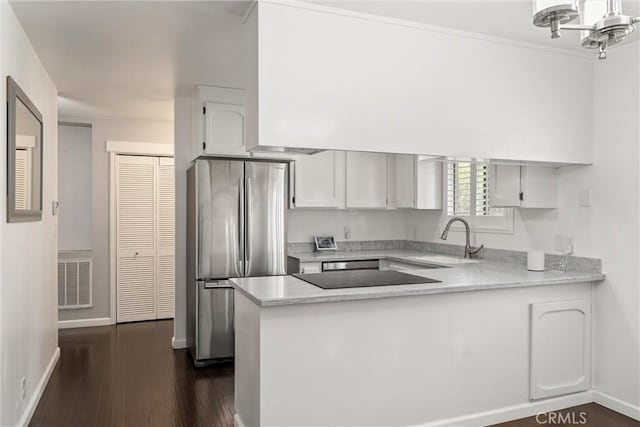 kitchen with visible vents, freestanding refrigerator, a peninsula, light countertops, and a sink