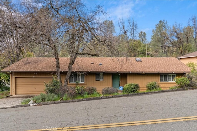 ranch-style house with driveway, an attached garage, and roof with shingles