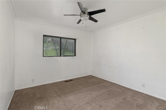 spare room with carpet, crown molding, visible vents, ceiling fan, and baseboards