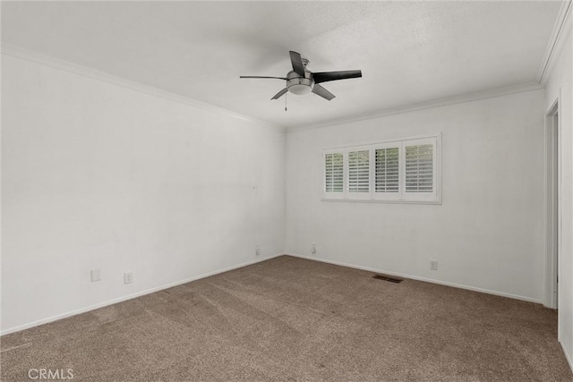 carpeted empty room with ornamental molding, visible vents, ceiling fan, and baseboards