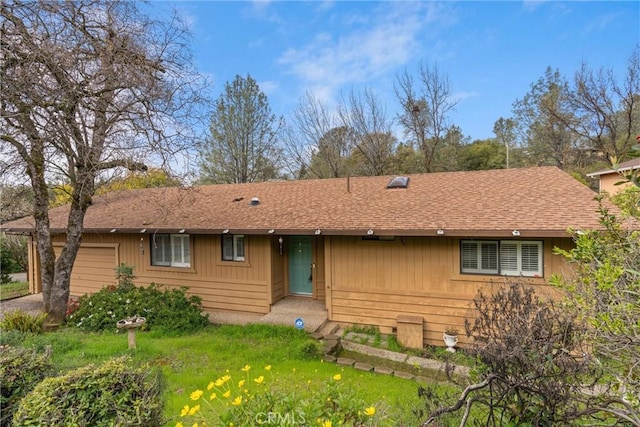 back of property featuring a garage and a shingled roof