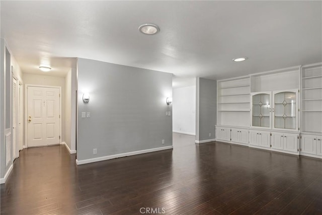 unfurnished room featuring baseboards and dark wood-type flooring