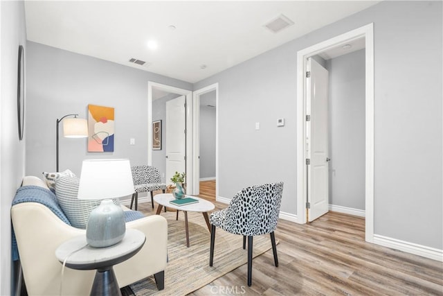 living area featuring light wood-type flooring, baseboards, and visible vents