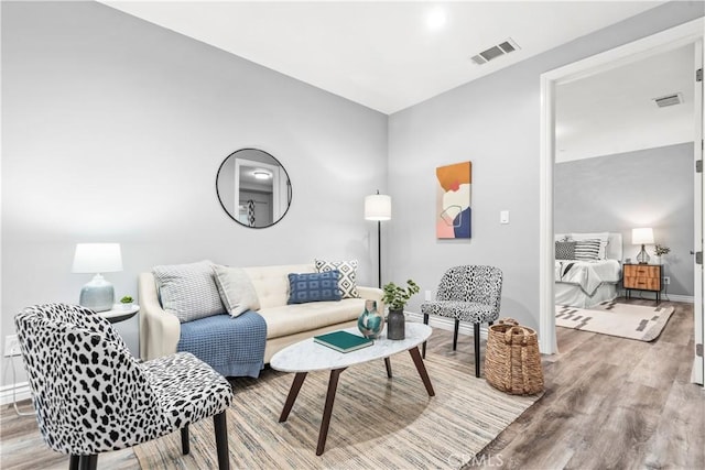 living room with wood finished floors, visible vents, and baseboards