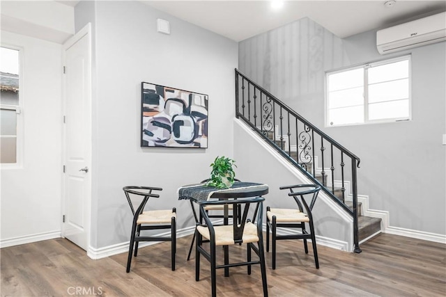 stairway with an AC wall unit, wood finished floors, and baseboards