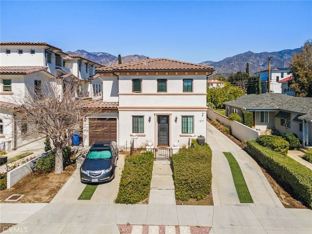 view of front of home with a fenced front yard, stucco siding, a mountain view, and concrete driveway