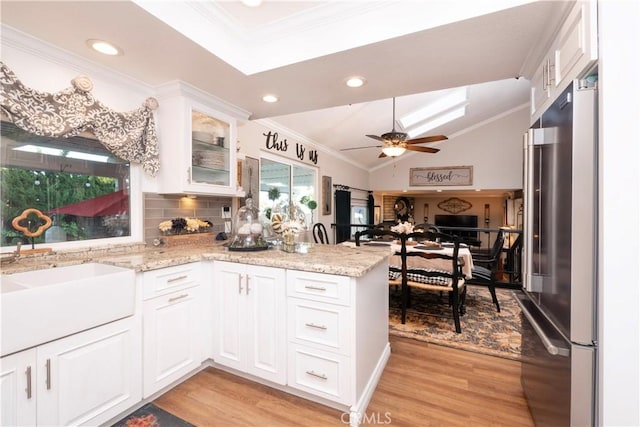 kitchen with crown molding, white cabinets, light wood-type flooring, a peninsula, and high end refrigerator