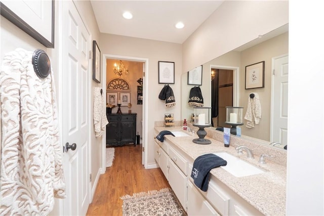 bathroom with recessed lighting, a sink, wood finished floors, baseboards, and double vanity