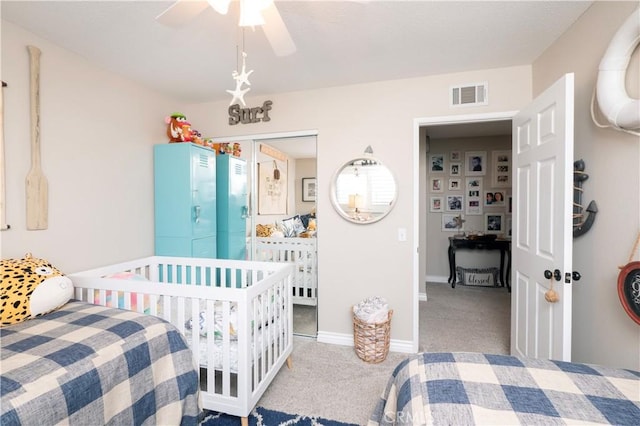 carpeted bedroom featuring a ceiling fan, visible vents, and baseboards