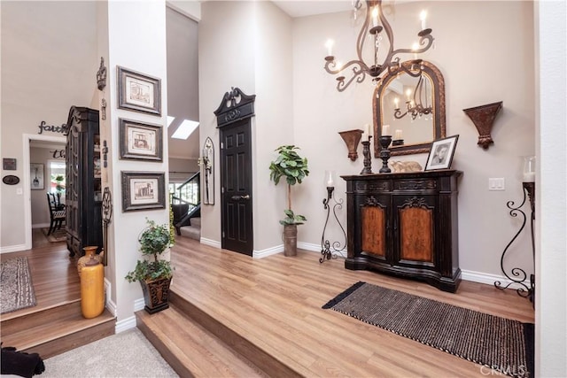 interior space with a chandelier, a high ceiling, wood finished floors, baseboards, and stairs