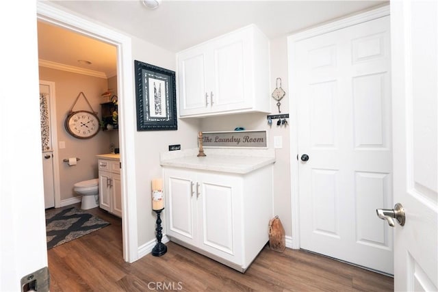 laundry room featuring crown molding, baseboards, and wood finished floors