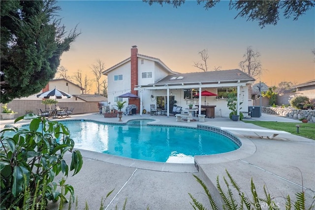 pool at dusk featuring a fenced in pool, a patio, a fenced backyard, cooling unit, and a diving board