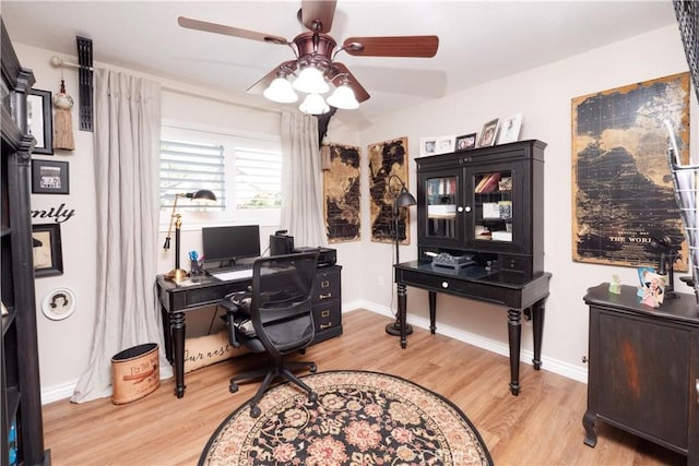 home office with light wood-style floors, baseboards, and a ceiling fan