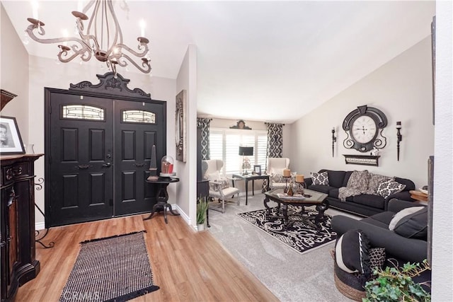 entryway featuring lofted ceiling, an inviting chandelier, light wood-style flooring, and baseboards