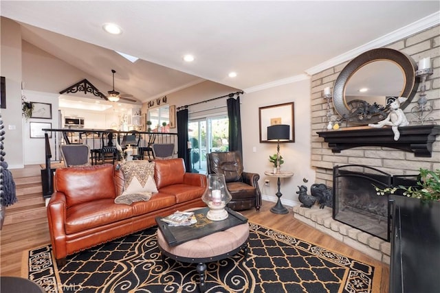 living area featuring baseboards, lofted ceiling with skylight, ornamental molding, wood finished floors, and a fireplace