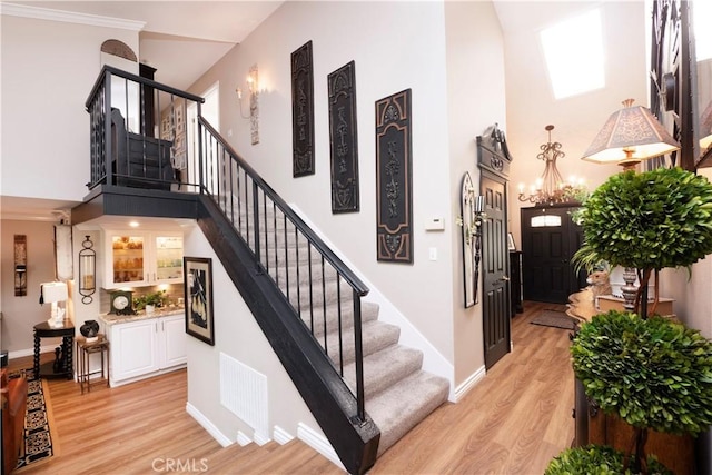 stairway with baseboards, a high ceiling, visible vents, and wood finished floors