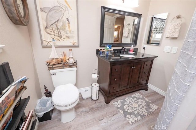 bathroom featuring vanity, wood finished floors, toilet, and baseboards