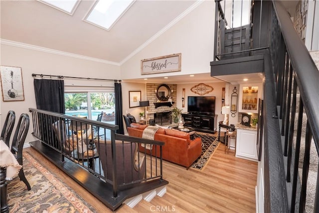 living area featuring light wood finished floors, a fireplace, ornamental molding, and high vaulted ceiling