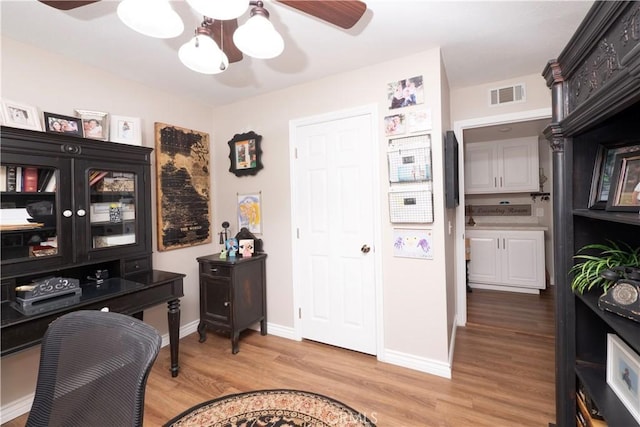 office space featuring baseboards, a ceiling fan, visible vents, and light wood-style floors