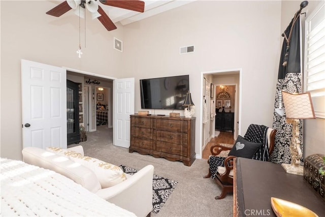 carpeted bedroom featuring beam ceiling, visible vents, connected bathroom, and a high ceiling