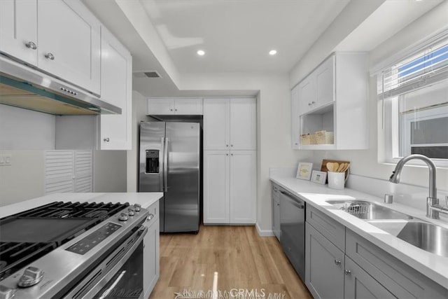 kitchen with a sink, stainless steel appliances, light countertops, under cabinet range hood, and visible vents
