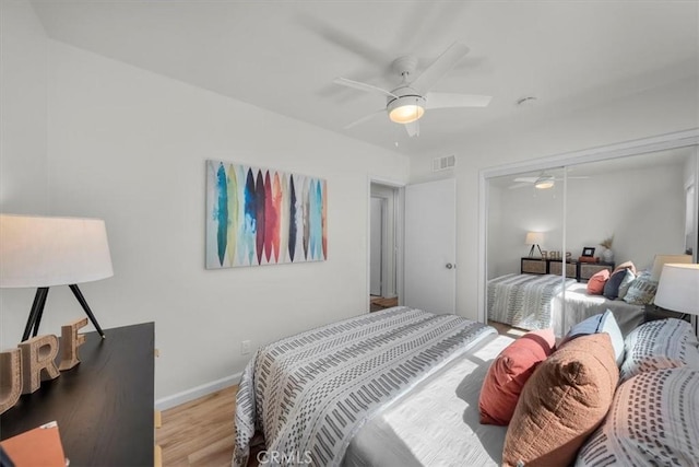 bedroom featuring wood finished floors, visible vents, a closet, baseboards, and ceiling fan