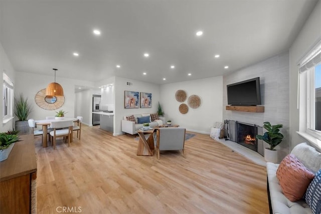 living area with a fireplace, recessed lighting, visible vents, light wood-type flooring, and baseboards