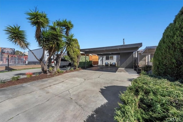 view of front facade with a carport, fence, and concrete driveway