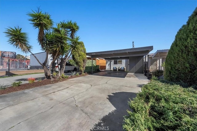 view of front of property featuring concrete driveway, fence, and a carport