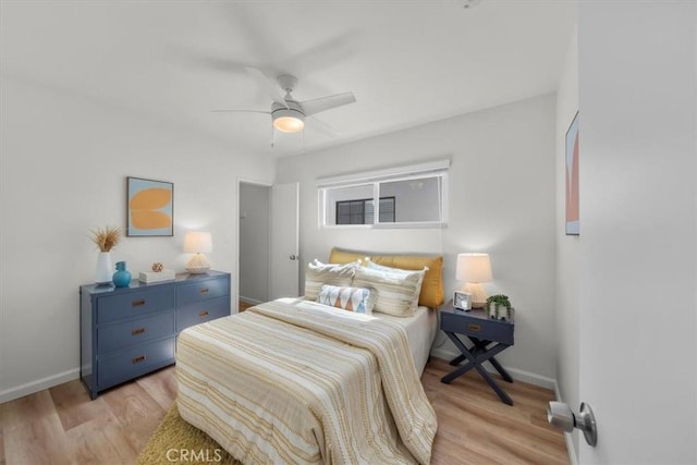 bedroom with ceiling fan, baseboards, and light wood-style floors