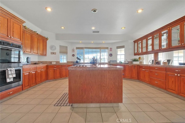 kitchen with a peninsula, light tile patterned floors, visible vents, and stainless steel appliances