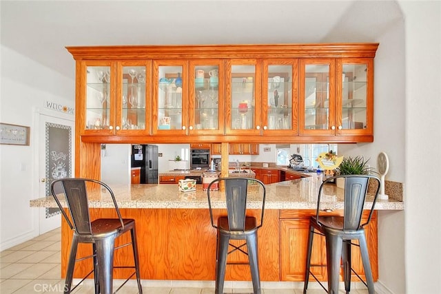 bar featuring black refrigerator with ice dispenser and light tile patterned floors