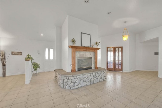 living room with a tile fireplace, french doors, baseboards, and light tile patterned floors