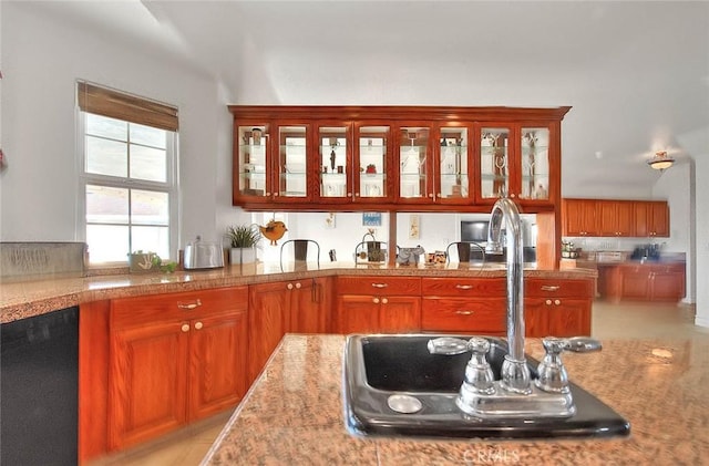 kitchen featuring dishwasher, a sink, glass insert cabinets, and brown cabinets