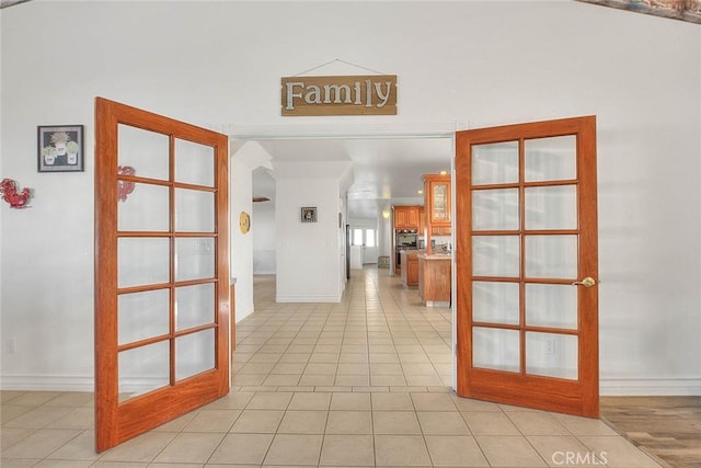 corridor featuring light tile patterned floors, baseboards, and french doors