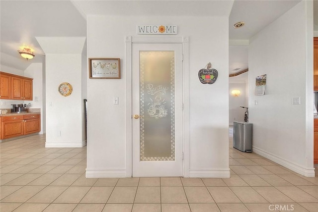 hallway featuring light tile patterned floors and baseboards