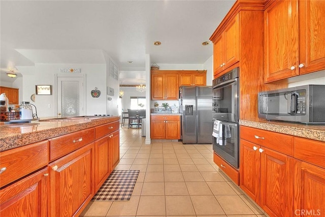 kitchen featuring appliances with stainless steel finishes, brown cabinets, tile countertops, and light tile patterned floors